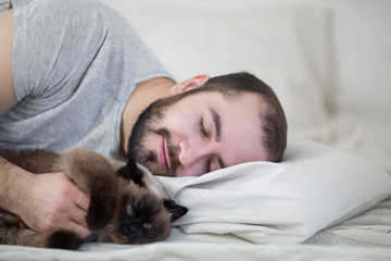 Man sleeps in bed with cat, has sweet sleep.