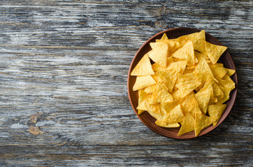 Nachos corn chips in a plate on a wooden table. Mexican food concept.