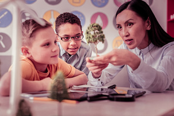 Curious students attentively looking on the model in teacher hands