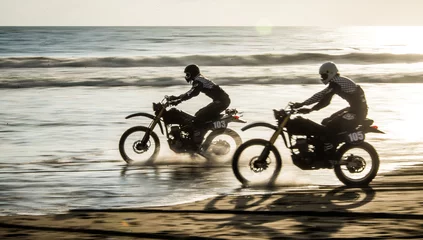 Wall murals Motorcycle Two friends racing on custom retro style cafe racer black motorcycles on the beach at sunset in Tabanan, Bali, Indonesia