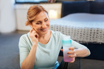 Pleasant mature lady with tied hair touching her chin