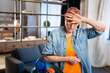 Unpleased woman in jeans shirt touching her forehead