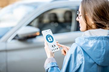Woman locking car using mobile application on a smart phone. Concept of remote control and car...