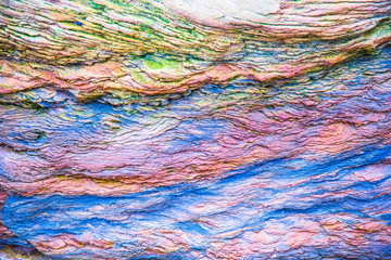 Obraz premium Multicolored rock wall from bottom sediments red orange dark rays crack smooth