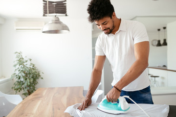 Young Happy Man Ironing Clothes