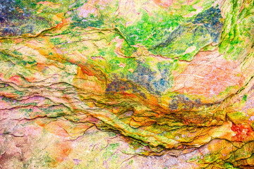 Multicolored rock wall from bottom sediments red orange dark rays crack smooth