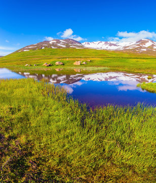  Blue lake water reflects snow in summer Iceland.