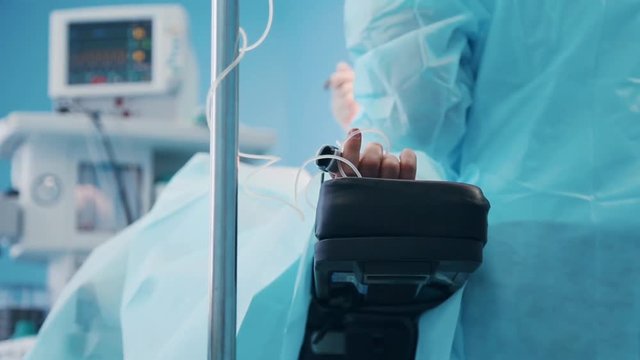 The concept of the operation, the team of surgeons, professional, the surgeon operates on the patient, the foreground of the patient's hand is connected to the heart monitors
