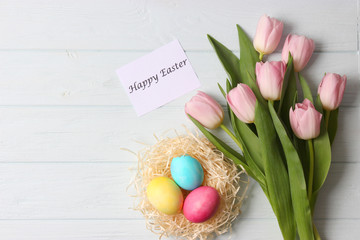 easter composition. Easter eggs and flowers on wooden color background top view. flatlay