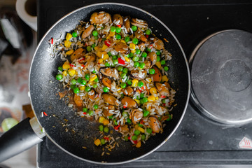 Fried frozen vegetable with rice and see food. Food remains in a black frying pan