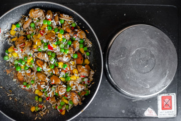 Fried frozen vegetable with rice and see food. Food remains in a black frying pan