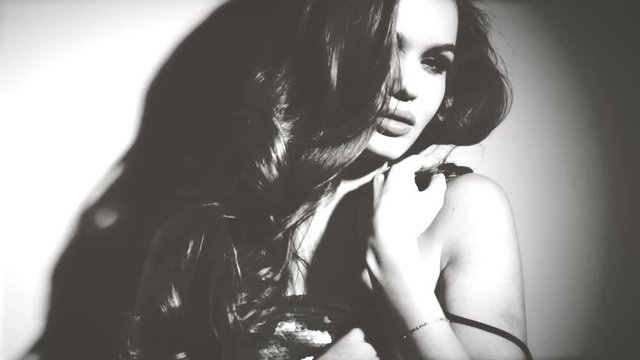 Black and White portrait of beauty sexy model girl. Beautiful seductive woman posing. Gorgeous Brunette girl in darkness. Beauty Glamour sensual lady with long curly hair posing in spotlight 4K Slowmo