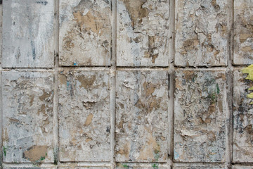 old gray wall tile background with remnants of paper advertising. old tile with peeling paint, abstract.