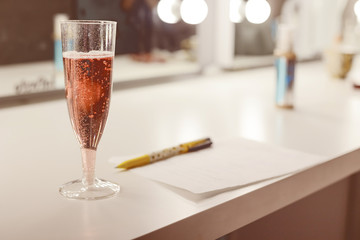 Glass of pink sparkling wine and note on a sheet in cage
