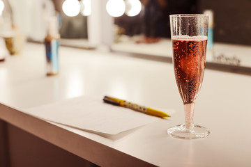 Glass of pink sparkling wine and note on a sheet in cage