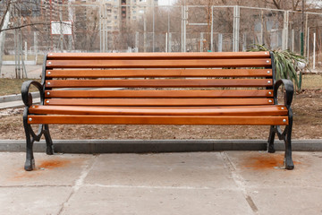 old fashioned wooden bench with black iron armrests on the background of the basketball court.