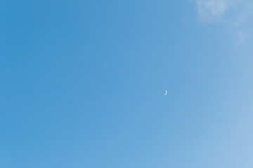 little evening moon on blue sky background, copy space for text. moon crescent on the clear sky background.