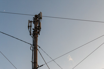 telecommunication pole with antennas and wires against the blue evening sky with a crescent, bottom...