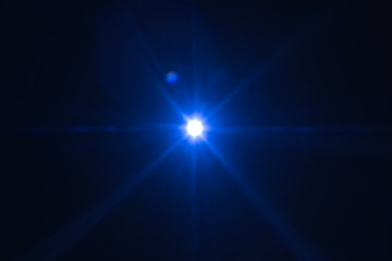 Single blue spark on black background. Lens flare effect. Defocused rays and lights.