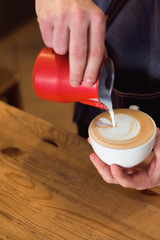 Barista pouring milk in coffee cup for make latte art.