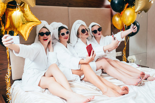 Bathrobe party girls taking selfie. Females leisure and lifestyle. Sunglasses and towel turbans on. Festive balloons decor.