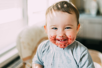 portrait of a child smiling with a dirty face in red jam