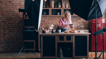 Fototapeta na wymiar Food blogger. Backstage photography. Female hobby and lifestyle. Young woman with smartphone shooting pastries.