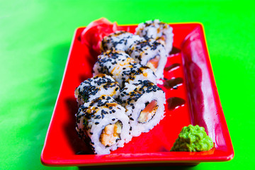 A portion of sushi on a red plate. green background