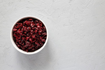 Dry organic cranberries in a bowl over concrete background, top view. Overhead, from above, flat lay. Copy space.