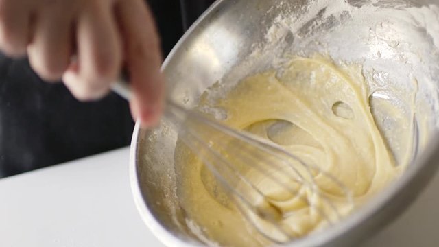 Slow motion crop shot of woman preparing homemade omelette mixing with whisk eggs.