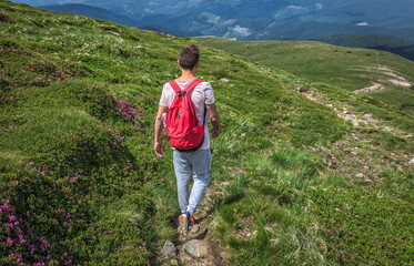 Fototapeta premium Summer boy or man traveler outdoor with backpack walks outside in mountains hike
