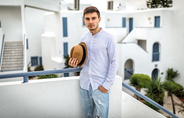 Young man in shirt of european appearance hat. Beautiful summer background in Italy or Greece Santorini