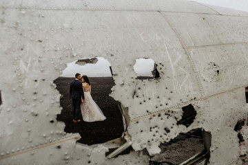 Beautiful wedding couple posing on beach near old plane