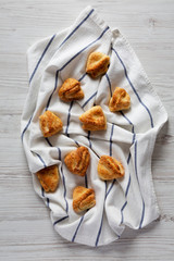 Fresh home-baked cottage cheese biscuits on cloth on white wood, top view. From above, overhead.