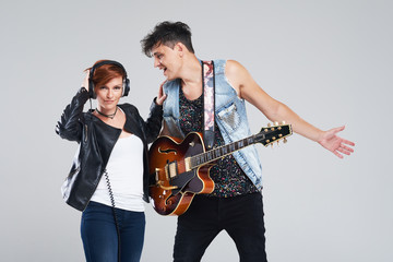 Obraz premium Musical artists sing and play electric guitar. Contemporary cover band. Isolated over grey background. Woman and man with headphones sing loudly