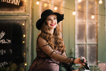 Beautiful young, stylish pregnant girl in black dress and hat sitting on a retro scooter