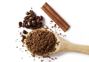 Instant coffee granules, beans and cinnamon stick with wooden spoon, isolated on white background, top view