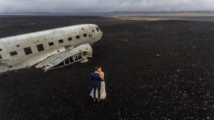 Beautiful wedding couple posing on beach near old plane