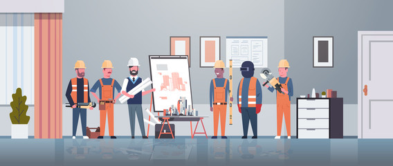 man architect engineer showing drawing building blueprint on easel board to construction workers group panning project team meeting presentation concept horizontal full length