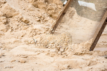 Sifting sand through a grid at a construction site. 