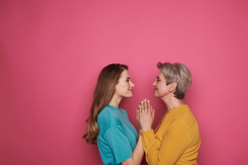 Smiling mother and daughter holding hands while looking at each other