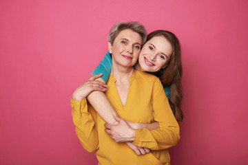 Beautiful woman with her daughter smiling and posing for camera - obrazy, fototapety, plakaty