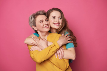 Beautiful woman and her charming daughter looking away in studio - obrazy, fototapety, plakaty