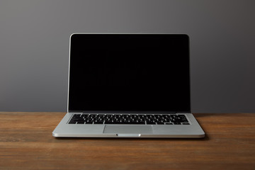 Laptop with blank screen on brown wooden surface isolated on grey