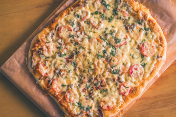 top view   fresh hot homemade pizza on wooden table,vintage toned,deadpan