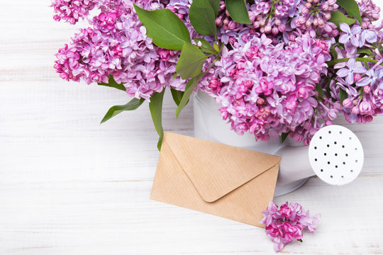 Lilac flowers and envelope on white wooden background, copy space