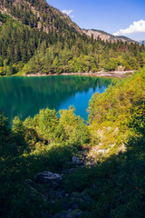Fototapeta na wymiar A huge panorama of the High-mountainous Baduk lake among the high Caucasian mountains and beautiful trees. Sunny summer day.