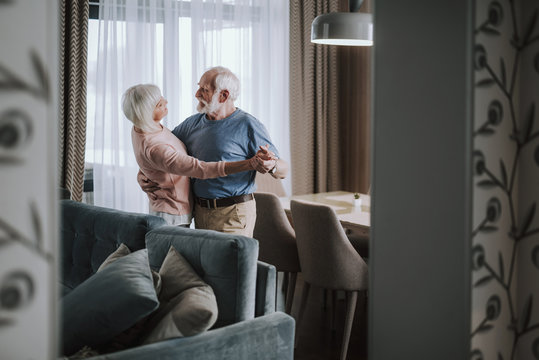 Positive elder couple dancing in living room