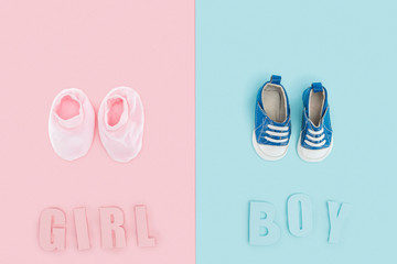 top view of boy and girl lettering and sneakers, booties on pink and blue background