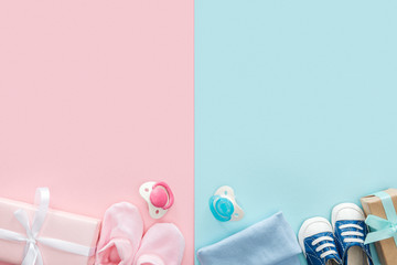 top view of pacifiers, gifts, hat, booties, sneakers on pink and blue background